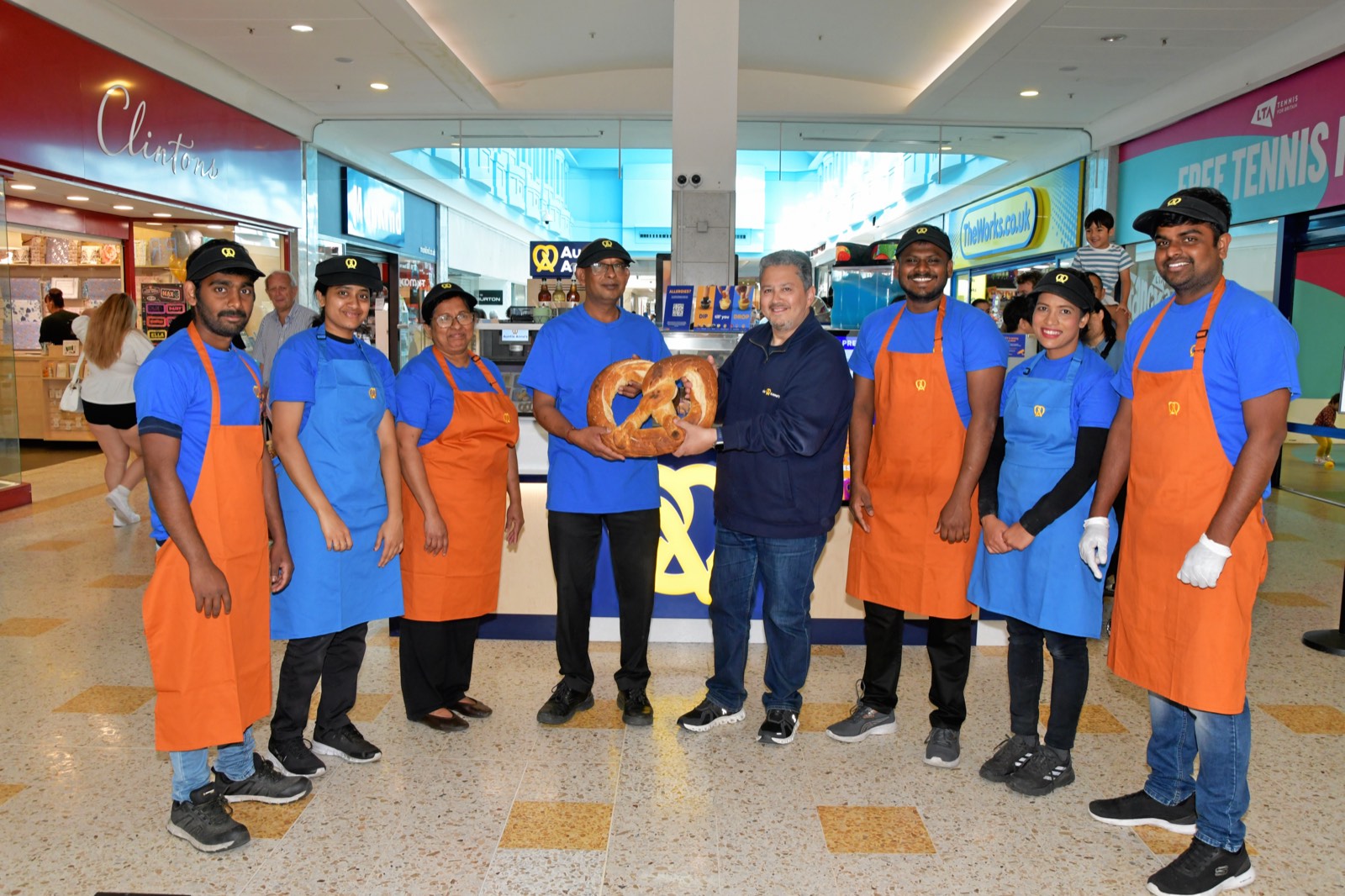 The Auntie Anne's team with the centre manager at the grand opening of their new store at The Beacon Eastbourne holding a giant pretzel